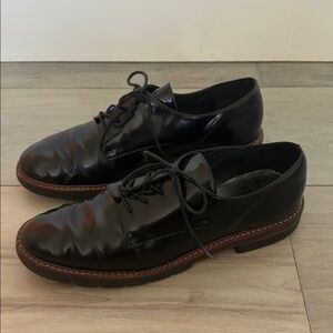 Stuart Weitzman Black patent leather oxfords with brown trim.